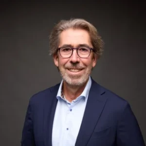 Porträt eines Anwalts der Kanzlei mit Brille, blauem Hemd und dunklem Sakko.